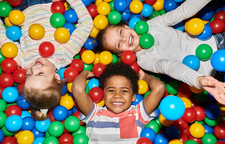 three happy kids playing in ballpit